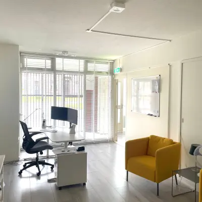 Modern kantoor met glaswand, twee bureaus en een comfortabele stoel op Wilhelminasingel 44-46 in Maastricht. Mogelijkheid tot kantoorruimte huren met een lichte, eigentijdse uitstraling.