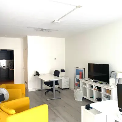 Kantoorruimte huren op Wilhelminasingel 44-46 in Maastricht met lichte vloer en gele fauteuils. Voorzien van bureau en kast, ideaal voor creatief werk of ontmoeting.