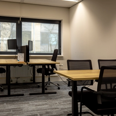 Kantoorruimte huren bij Gooimeer 1, Naarden: moderne werkplekken met houten bureaus en ergonomische stoelen, ideaal voor productief werk. Grote ramen zorgen voor natuurlijk licht.