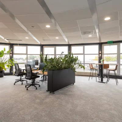 Ruime, lichte kantoorruimte met meerdere bureaus en planten op Patroonstraat 13, Nijkerk. Ideaal voor het huren van een inspirerende werkplek.