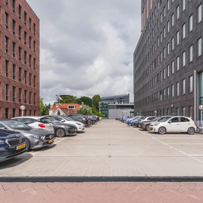 Parkeerplaats voor het kantoorpand op Laan van Zuid Hoorn 70, Rijswijk, met diverse geparkeerde auto's en omringende kantoorgebouwen.