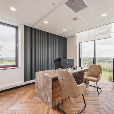 Kantoorruimte met houten vloer, marmeren bureau, comfortabele stoelen en uitzicht op Rijswijk. Geschikt voor werken en kantoorruimte huren.