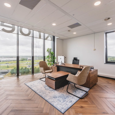 Moderne kantoorruimte in Rijswijk met groot raam, uitzicht over stad. Kantoorinrichting met bureau, stoelen en tapijt. Geschikt voor kantoorruimte huren.