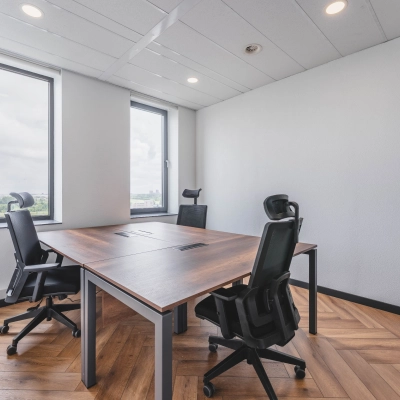 Lichte en moderne kantoorruimte met houten vloer en grote ramen, voorzien van vier bureaustoelen en een tafel, in Rijswijk.