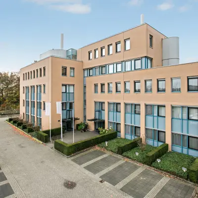 Uitzicht op modern kantoorpand aan Laan van Brabant 70-86 in Roosendaal, omgeven door parkeerplaatsen en groenvoorzieningen.