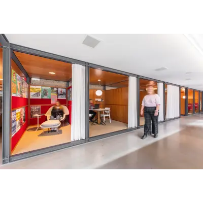 Kantoorruimte huren op Hofplein 20 in Rotterdam Centraal Station met een kleurrijk interieur, waar twee personen zakelijke gesprekken voeren in moderne cabines.