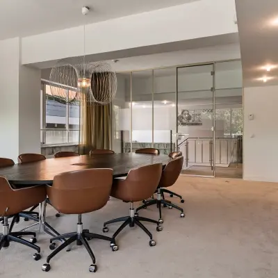 Vergaderruimte met grote ovale tafel en bruine stoelen in kantoorpand aan de Coolsingel 104, Rotterdam Centrum. Kantoorruimte huren met ruime vergaderfaciliteiten.