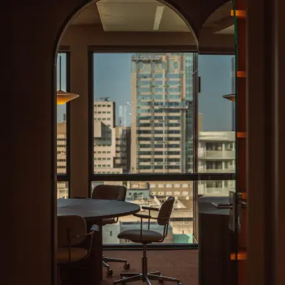 Lichte kantoorruimte met vergadertafel en stoelen, uitkijkend over de skyline van Rotterdam. Grote ramen bieden een prachtig uitzicht, ideaal om te huren op Coolsingel 139, Rotterdam Centrum.