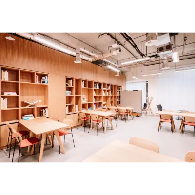 Lichte kantoorruimte in kantoorpand, Hoogstraat 185, Rotterdam Centrum, met houten tafels en stoelen, omringd door open boekenplanken. Ideaal voor wie kantoorruimte wil huren met een moderne uitstraling.