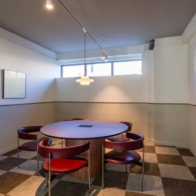 Vergaderruimte in een kantoorpand op Stadhuisplein 9-23 in Rotterdam Centrum met een ronde tafel en rode stoelen. Deze kantoorruimte is ontworpen voor creatieve meetings en brainstormsessies.