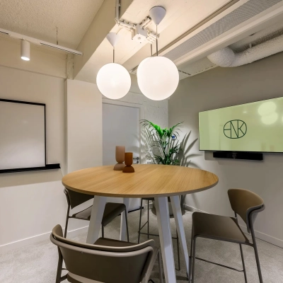 Moderne kantooruimte aan Vasteland 42-110 in Rotterdam Centrum, voorzien van een ronde tafel met stoelen, een muurbeeldscherm en decoratieve lampen. Ideaal voor wie een kantoorruimte wil huren.