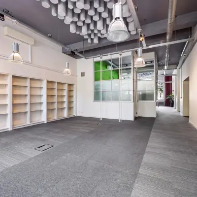Ruime kantoorruimte in Rotterdam Centrum met industriële look, grijze vloerbedekking en opvallende plafondornamenten. Perfecte plek om een kantoor te huren dankzij de open indeling en praktische opbergmogelijkheden.