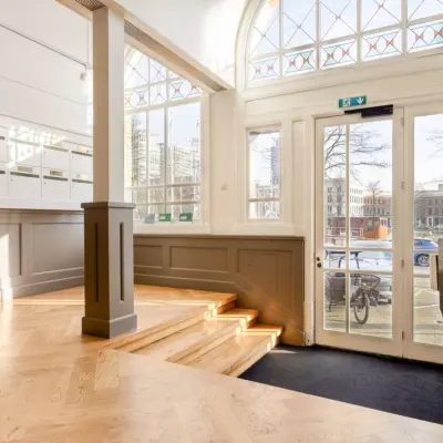 Ingang van het kantoorpand op Veerhaven 7, Rotterdam Centrum met hoge ramen die veel licht binnenlaten en houten vloer.
