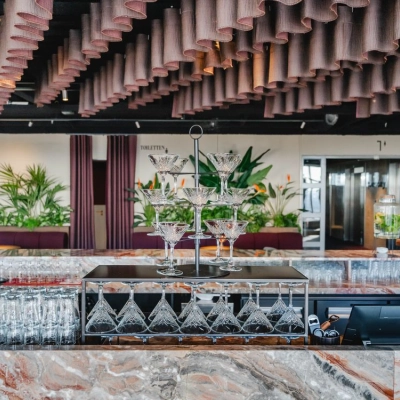 Chique kantoorpand op Weena 690 in Rotterdam Centrum met een elegant ingerichte bar en planten die de ruimte een levendige sfeer geven. Perfect voor kantoorruimte huren.