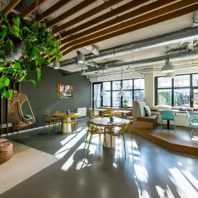 Moderne kantoorruimte aan de Westblaak 180 in Rotterdam Centrum, met veel natuurlijk licht en een stijlvolle inrichting met hangplanten en diverse zitplekken. Ideaal voor het huren van inspirerende werkplekken.