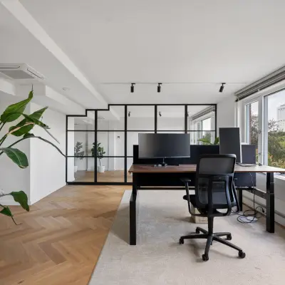 Moderne kantoorruimte huren op Westplein 12, Rotterdam Centrum, met grote ramen, houten vloer en werkruimte met bureaustoel en computeropstelling.