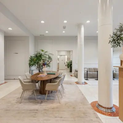 Moderne kantoorruimte met een stijlvolle tafel en stoelen, omringd door groene planten op Westplein 12, Rotterdam Centrum. Helder verlicht met lift en comfortabele zithoek.