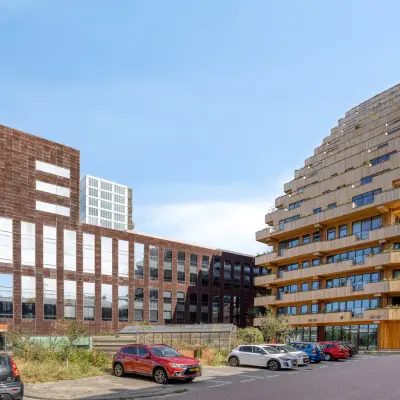 Moderne kantoorpand aan de Kratonkade 7-27 in Rotterdam Delfshaven, omgeven door andere eigentijdse gebouwen en met een ruime parkeerplaats ervoor.