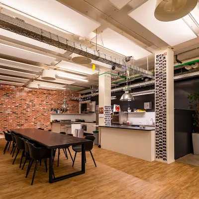 Moderne kantoorruimte huren in Rotterdam Delfshaven, Kratonkade 7-27. Een open ruimte met een keuken en een lange tafel, perfect voor vergaderingen en samenwerking.