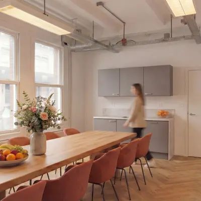 Gemeubileerde kantoorruimte huren aan Lloydstraat 5, Rotterdam Delfshaven, met een lange houten tafel en moderne stoelen in een lichte ruimte.