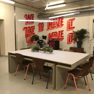 Moderne kantoorruimte huren in Rotterdam Delfshaven, met stijlvolle meubels en inspirerende muurtekening. Ideaal voor creatieve meetings en samenwerking.