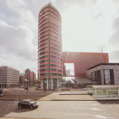 Buitenzijde van het opvallende kantoorpand op Wilhelminaplein 1-40 in Rotterdam Kop van Zuid, met zicht op de karakteristieke ronde toren en omliggende architectuur.