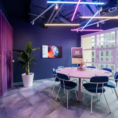 Moderne kantoorscheidingsruimte in Rotterdam Kop van Zuid, Wilhelminaplein 1-40, met kleurrijke verlichting en stijlvolle, ronde tafel voor creatief overleg. Ideale plek voor kantoorruimte huren.