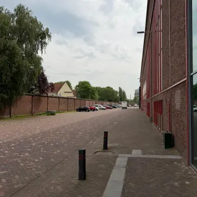 Kantoorpand aan de Scheepsbouwweg 29 in Rotterdam Waalhaven, met een lange, rode gevel en geparkeerde auto's langs de straat. Geschikt voor kantoorruimte huren.