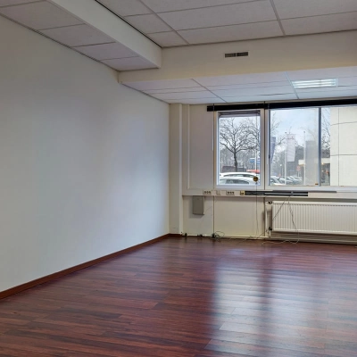 Ongemeubileerde kantoorruimte op de Brauwweg 52-66 in Schiedam met houten vloeren en een raam met uitzicht naar buiten.