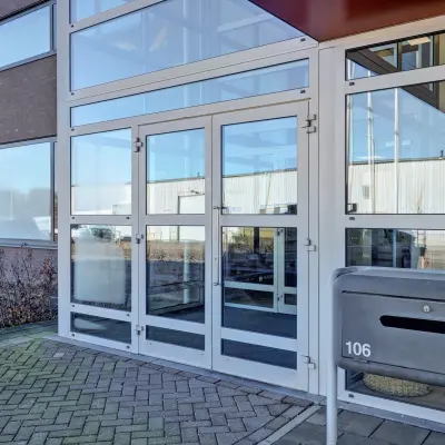 Buitenkant van een modern kantoorpand gelegen aan het Fischerpad 106 in Sittard, met glazen entree en ruime parkeerplaats. Ideale plek om kantoorruimte te huren.