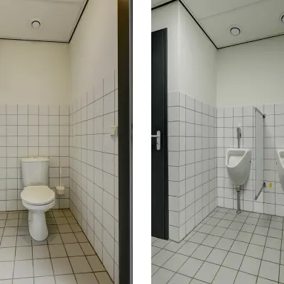 Kantoortoilet met witte tegelwanden en vloer op Fischerpad 106 in Sittard, ideaal voor bedrijven die kantoorruimte willen huren. Praktische sanitaire voorzieningen completeren het kantoorpand.