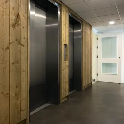 Gang met liftdeuren en houten accenten in een kantoorpand aan de Curieweg 9, Spijkenisse.
