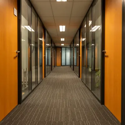 Glazen kantoorruimtes aan een centrale gang op Curieweg 9, Spijkenisse, klaar voor verhuur. De kantoorpand beschikt over houten deuren en moderne verlichtingsplafonds.