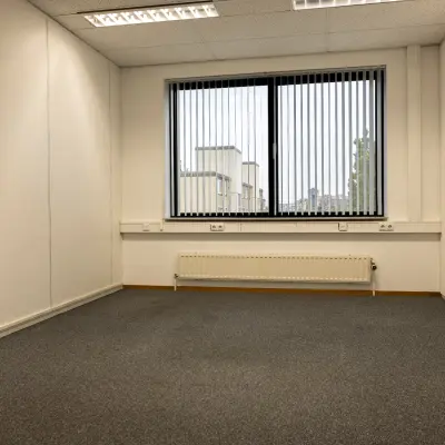 Leeg kantoor op Curieweg 9, Spijkenisse, ideaal voor kantoorruimte huren. Neutrale muren en raam met jaloezieën.