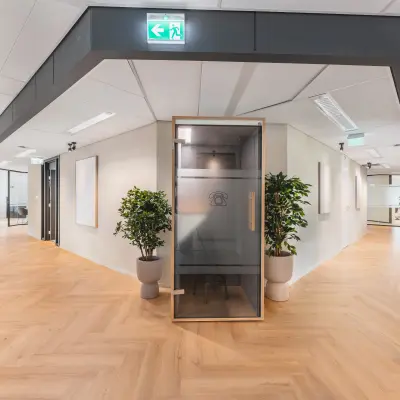 Moderne kantoorruimte met glazen wanden en houten vloer op Leidseveer 2-10, Utrecht Centraal Station, ideaal voor werkruimten huren.