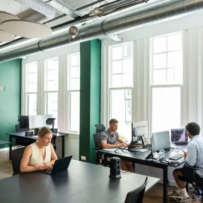 Kantoor aan de Oudegracht 161 in Utrecht Centrum met drie mensen bezig met hun werk. Grote ramen bieden veel lichtinval. Geschikt voor wie kantoorruimte wil huren in een levendig kantoorpand.