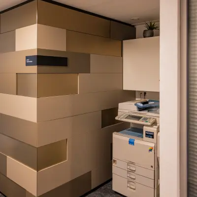 Binnen een kantoorpand op Middenburcht 136, Utrecht Leidsche Rijn staat een kopieerapparaat naast een modern ontworpen muur. Ideale plek voor bedrijven om hun dagelijkse taken efficiënt uit te voeren.