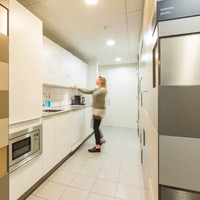 Kantoorruimte huren in Utrecht Leidsche Rijn met een moderne pantry, voorzien van keukenapparatuur waar een persoon een kopje koffie zet.
