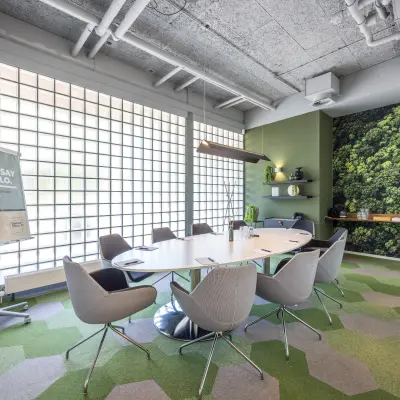 Moderne vergaderruimte in een kantoorpand aan de Goeman Borgesiuslaan 77, Utrecht Noord. De ruimte heeft groene accenten, een ovale tafel en comfortabele stoelen, ideaal voor kantoorruimte huren.