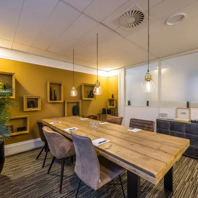 Stijlvolle kantoorruimte met houten tafel en moderne verlichting, ideaal voor vergaderingen op Goeman Borgesiuslaan 77 in Utrecht Noord. Een fijne plek om kantoorruimte te huren met een warme uitstraling.