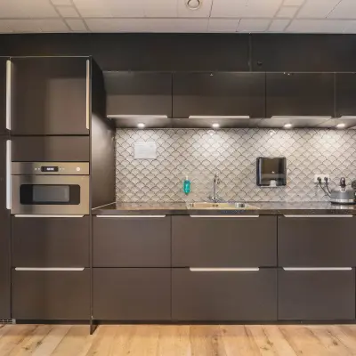 Moderne pantry in kantoorpand gelegen aan de Goeman Borgesiuslaan 77 in Utrecht Noord, met strakke donkerbruine keuken en visgraatmaur. Ideaal voor bedrijven die kantoorruimte willen huren.