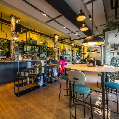 Vrolijke en groene kantoorruimte in Utrecht Noord met houten vloer, planten en moderne meubels. Een persoon zit ontspannen in de ruimte, geschikt voor werk of overleg.
