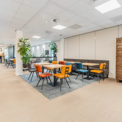 Moderne kantoorruimte huren op Orteliuslaan 850, Utrecht Papendorp, met kleurrijke stoelen en tafels, ruime indeling en veel lichtinval, geschikt voor diverse zakelijke activiteiten.