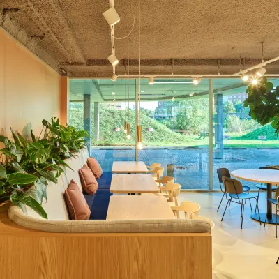Moderne kantoorruimte met grote ramen, groene planten en zitplaatsen in een eigentijds kantoorpand in Utrecht. Geschikt voor bedrijven die kantoorruimte willen huren op Van Deventerlaan 30-40.