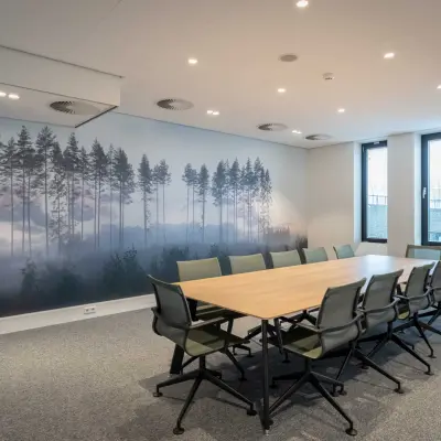 Vergaderruimte in kantoorpand op Van Deventerlaan 31-51, Utrecht Papendorp, met lange houten tafel en groene stoelen. Huur kantoorruimte met uitzicht op muurkunst van een boslandschap.