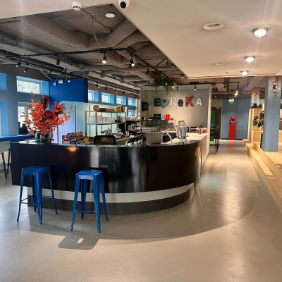 Lichte kantoorruimte huren op Daltonlaan 200 in Utrecht Rijnsweerd met een moderne bar, blauwe krukken en kleurrijke decoraties voor een informele werk- of pauzeomgeving.