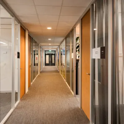 Heldere gang in kantoorpand met glazen wanden en houten deuren op Winthontlaan 200, Utrecht Zuid. Ideaal voor kantoorruimte huren.