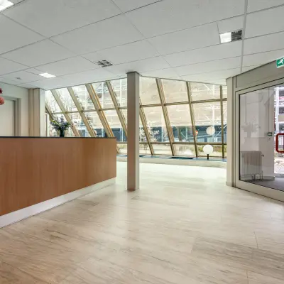 Ingang van een kantoorpand op De Run 1141-1157 in Veldhoven met grote ramen, ontvangstbalie en bloemenvaas. Ideaal voor bedrijven die kantoorruimte willen huren.