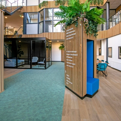 Interieur van modern kantoorpand op De Run 4312, Veldhoven, met kleurrijke muren, groen tapijt en een rustige zithoek waar je kantoorruimte kunt huren.