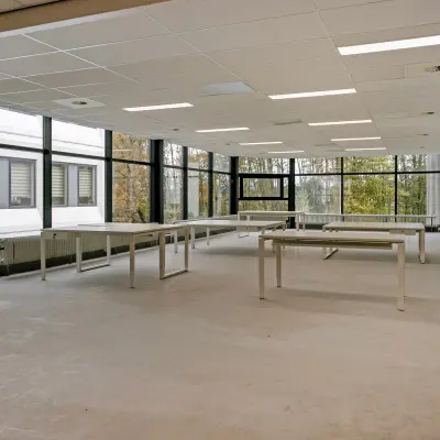 Lichte kantoorruimte huren bij De Run 4312 in Veldhoven, met grote ramen en uitzicht op bomen. Geschikt voor diverse kantooractiviteiten.